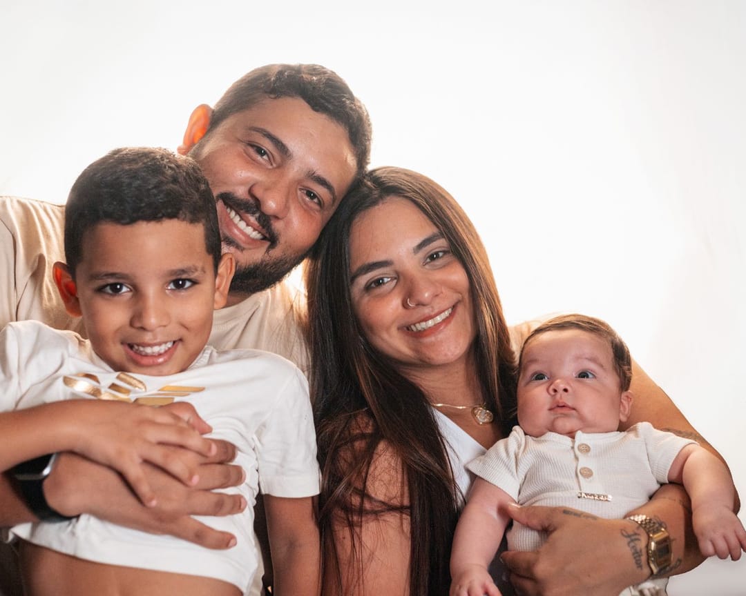 Pai, mãe e dois filhos sorrindo abraçados